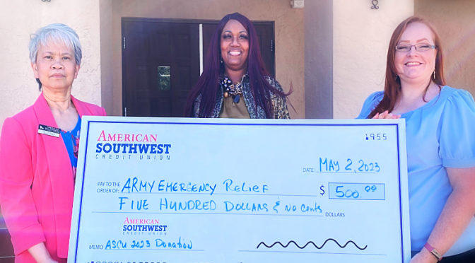 Fe Currie holds giant check for Army Emergency Relief Fund